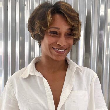 A smiling woman with a curly short bob hairstyle