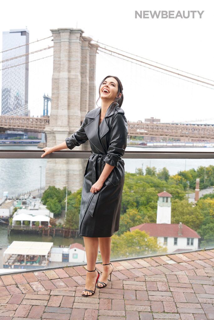 Katie Lee in black leather coat in front of the Brooklyn Bridge