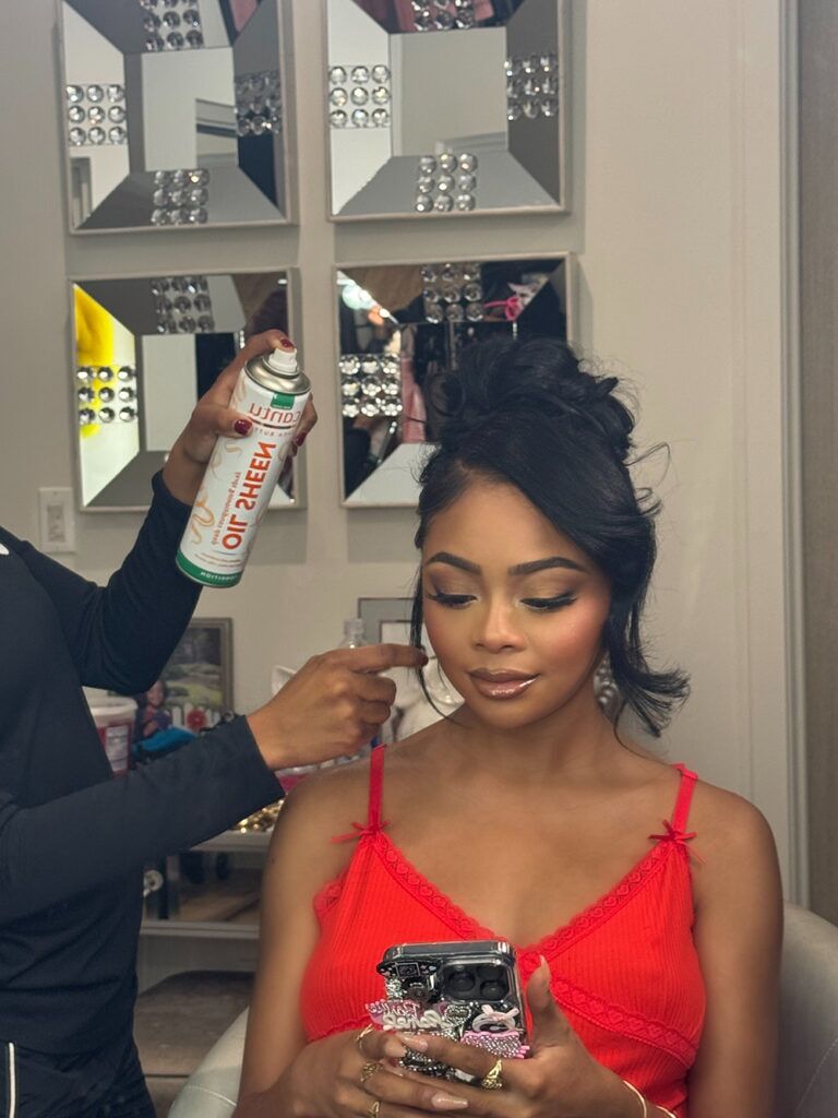 Shai Jackson's hair being sprayed with Cantu Sheen Oil