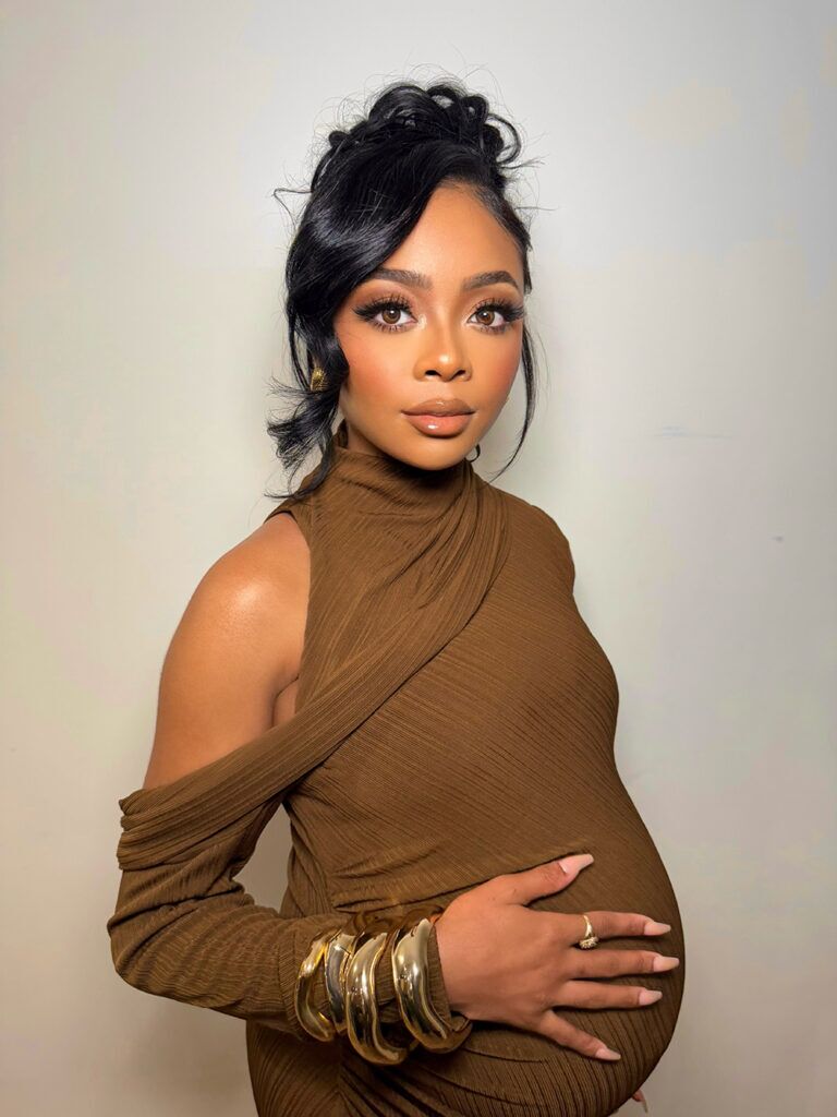 Pregnant Skai Jackson wearing a brown dress and gold jewelry