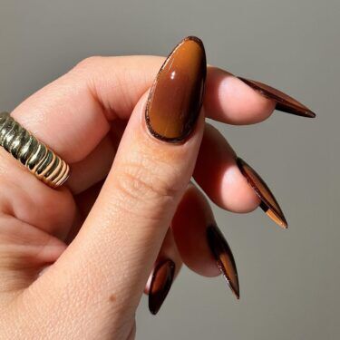 A thumbnail with brown and tan aura nail design.