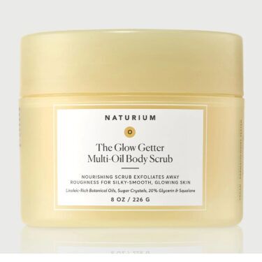 Naturium The Glow Getter Multi-Oil Body Scrub in a pale yellow jar, a moisturizing body exfoliator formulated to smooth dry skin and enhance glow, featured in a roundup of the best body exfoliators.
