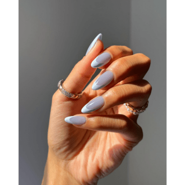 A close up of a woman's hand with her manicured nails and rings on multiple fingers